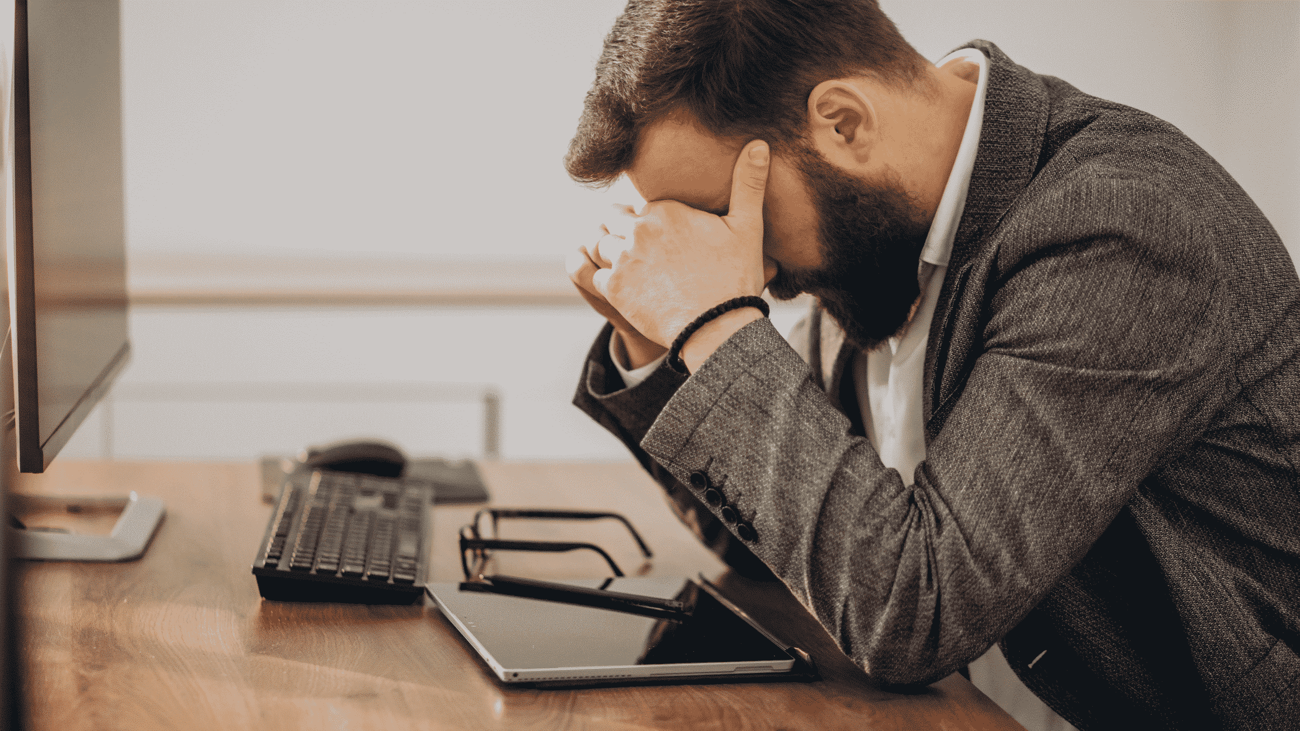 Homme triste et pensif avec la tête dans ses mains devant son écran d'ordinateur