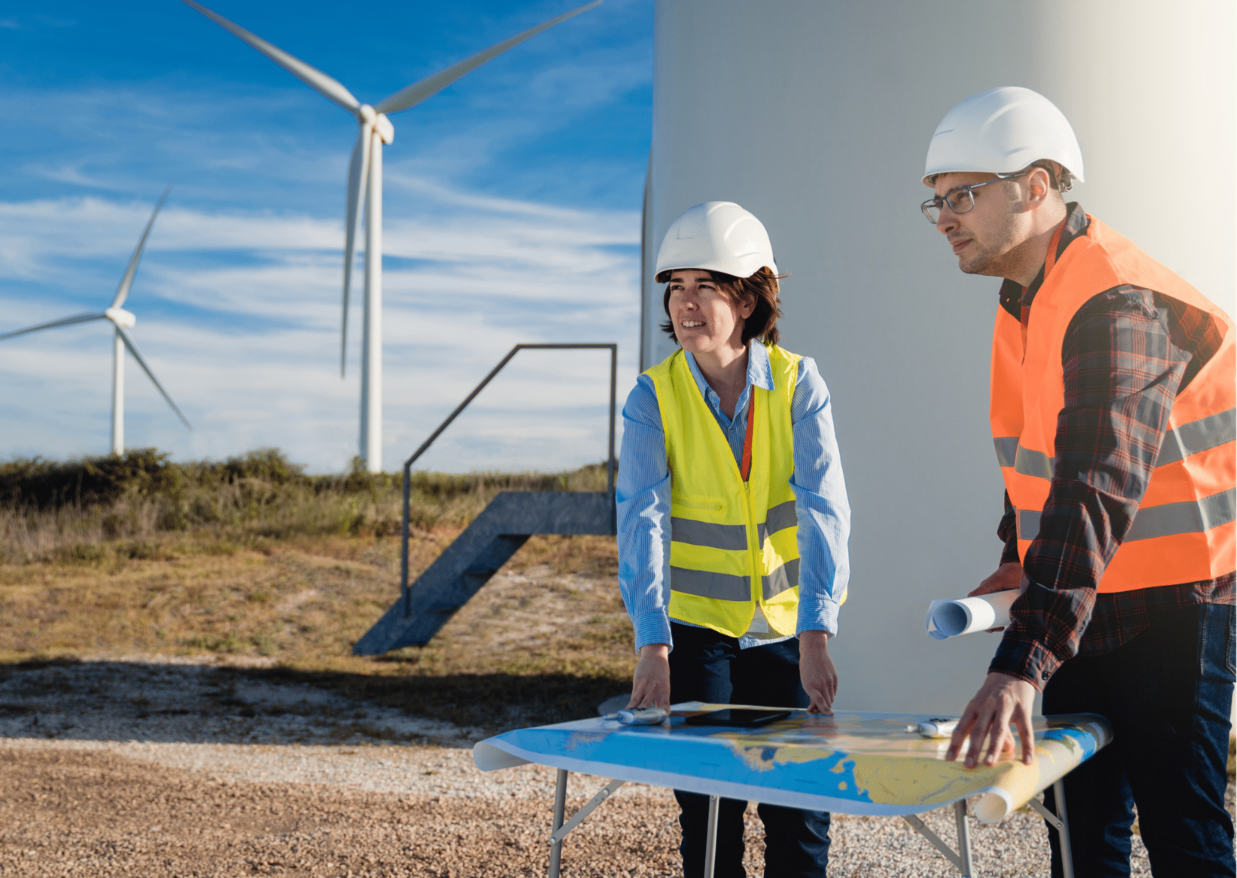 Femme et homme avec un casque de chantier avec des éoliennes en fond pour illustrer les 6 étapes à suivre pour trouver un emploi dans les EnR.