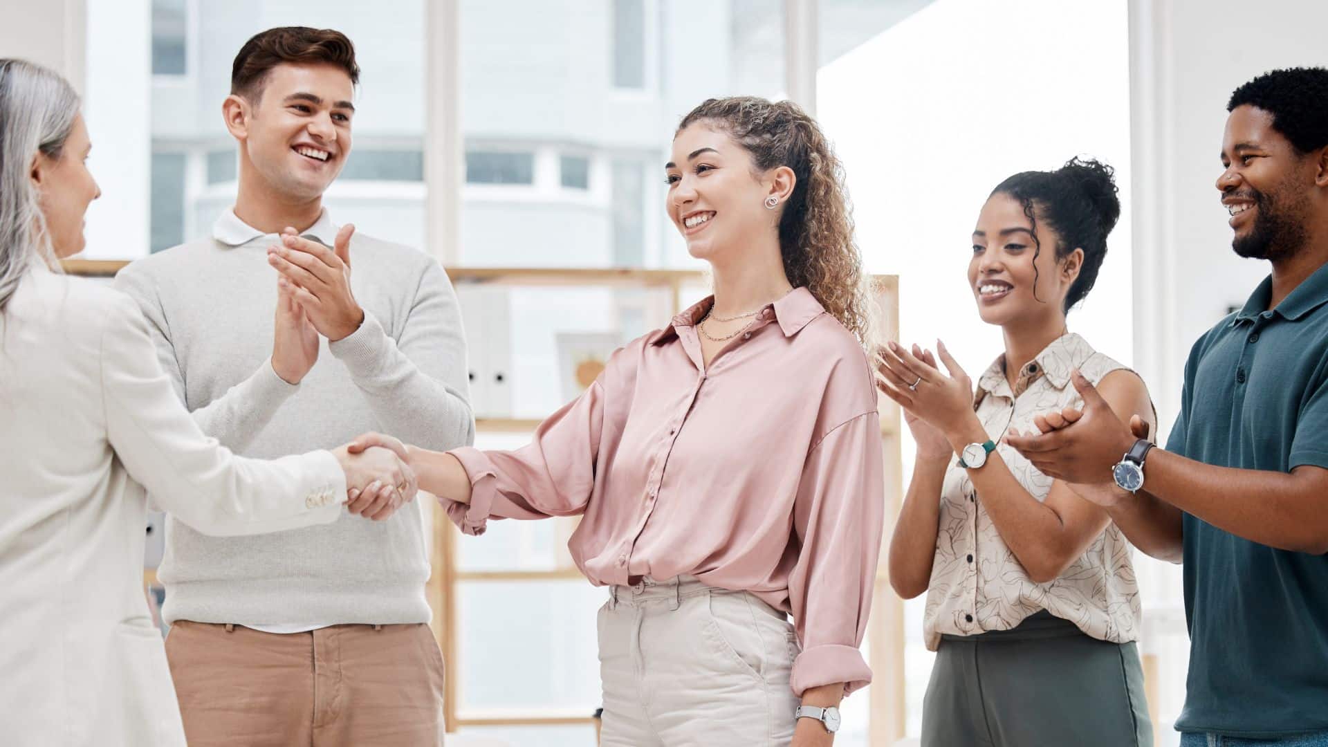 Un groupe de personnes qui applaudissent dont deux qui se serrent la main pour illustrer le fait de l'importance de mener à bien un onboarding