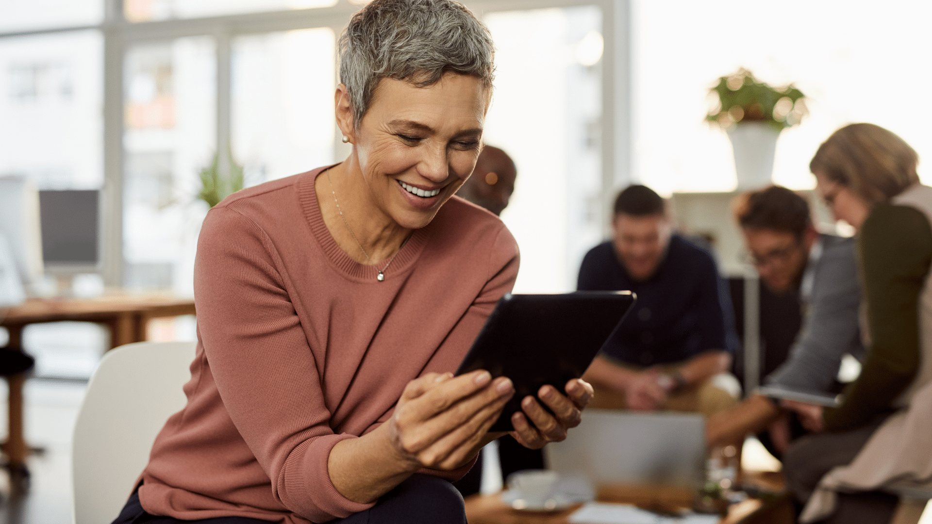 Femme qui sourit devant une tablette pour illustrer les conseils pour réussir un entretien pour un poste de direction